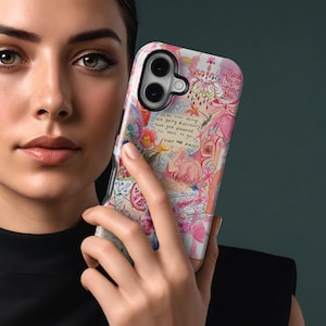 May include: A phone case with a colorful, artistic design featuring pink, white, and red watercolor elements. The case has a floral and bunny motif, with handwritten text that reads "Thank You for Being You" and "Trust the process."