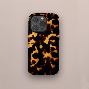 May include: A smartphone case with a tortoiseshell pattern. The case has a glossy finish and a dark border. The pattern features a mix of dark brown and golden yellow shapes, creating a natural, organic look. The case has a camera module with three lenses.