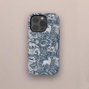 Op de afbeelding: Een marineblauwe telefoonhoes met een wit bosontwerp met herten, vossen en bomen. De hoes heeft een glanzende afwerking en een uitsparing voor de camera. Het patroon herhaalt zich met bosdieren en bladeren.