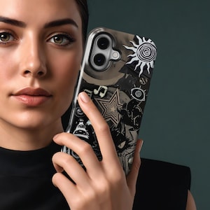 Puede incluir: Funda de tel&eacute;fono en blanco y negro con un sol, notas musicales, una estrella y un dise&ntilde;o de ojo. La funda tiene un fondo oscuro y est&aacute; sujeta en la mano de una persona.
