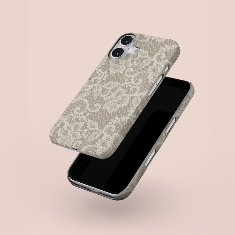 May include: Two phone cases with a beige lace pattern. One case is slightly lifted, revealing the phone's black screen. The cases have a neutral color palette, with a soft pink background.
