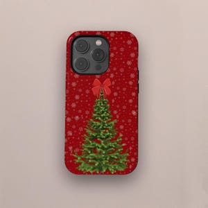 Może przedstawiać: Czerwone etui na telefon z motywem choinki. Etui ma zieloną choinkę z czerwoną kokardą na górze, na czerwonym tle z białymi płatkami śniegu. Etui ma czarną obwódkę i wycięcia na aparat.
