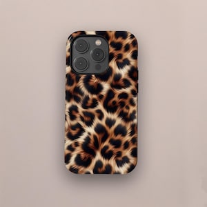 Puede incluir: Una funda de teléfono con diseño de estampado de leopardo. La funda presenta un patrón de manchas marrones y negras sobre un fondo beige. La funda tiene un acabado brillante y un recorte para la cámara.