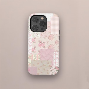 May include: A phone case with a patchwork design featuring various floral patterns, pink gingham, and textured pink squares. The case has a camera cutout and a black border.