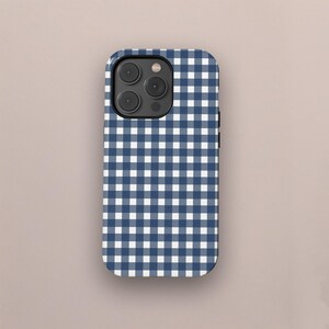 May include: A navy blue and white gingham pattern phone case. The case has a rectangular shape with rounded corners and a camera cutout. The pattern is a classic checkered design, with alternating squares of navy blue and white. The case is designed to fit a smartphone.