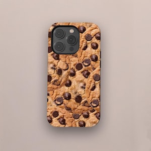 May include: A phone case featuring a close-up image of a chocolate chip cookie. The case has a brown and tan background with dark brown chocolate chips scattered throughout. The case has a black camera lens area.