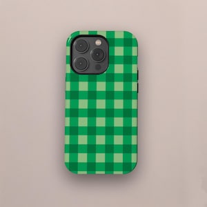 Puede incluir: Una funda de teléfono a cuadros verdes y verde claro. La funda tiene un acabado brillante y un recorte para la cámara. El patrón de cuadros es un diseño clásico, perfecto para añadir un toque de estilo a tu teléfono.