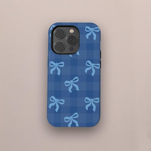 Pode incluir: Uma capa de telefone azul com um padrão xadrez branco e azul e laços azuis claros.