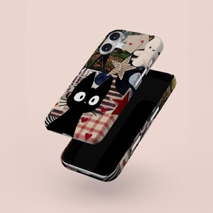 May include: A phone case with a collage design featuring a black cat, red hearts, and a white stuffed animal. The case has a mix of patterns and textures, including plaid and star shapes. The word "vision" is visible on the case.