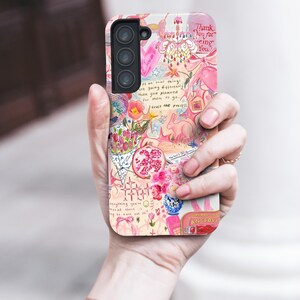 May include: A phone case with a colorful, whimsical design. The case features a collage of pink and white illustrations, including flowers, a rabbit, and text that reads "Thank You for being You" and "trust the process."