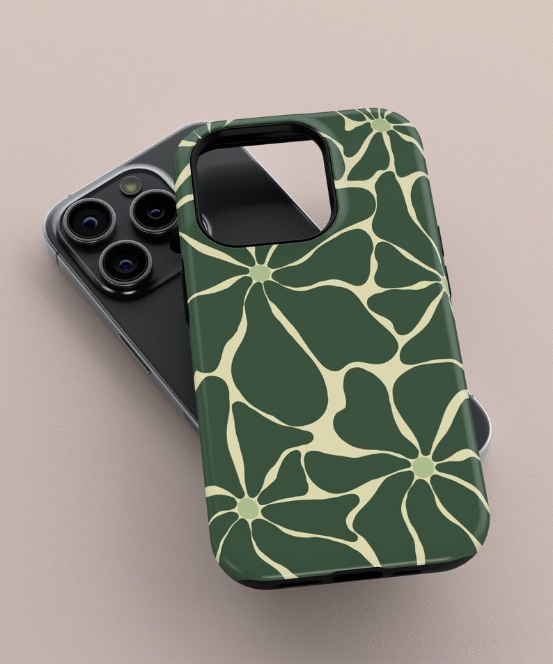 May include: A dark green phone case featuring a cream floral design. The case is placed on a black phone with multiple camera lenses. The floral pattern consists of large, stylized flowers, giving a retro feel. The case is made of a glossy material.