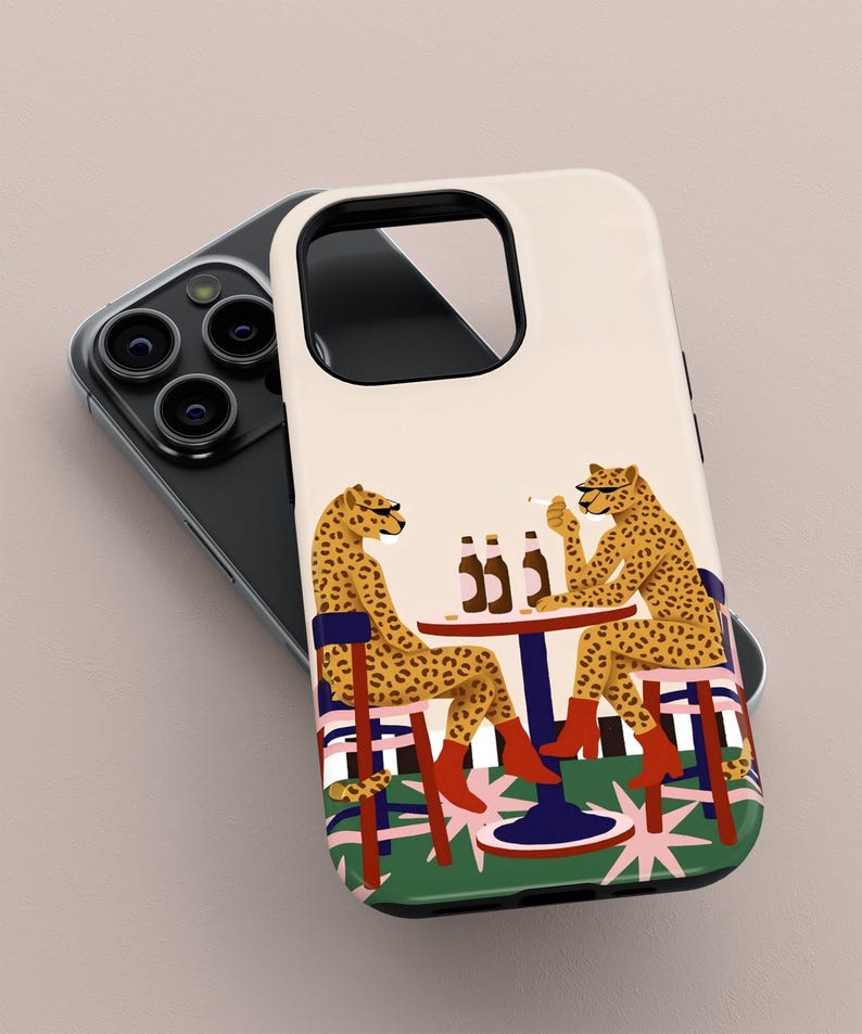 May include: A phone case with a quirky illustration of two cheetahs at a table with bottles and cigarettes. The cheetahs are wearing boots and sitting on chairs. The background has a green and pink design.