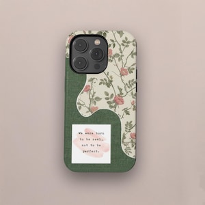 Könnte beinhalten: Handyhülle mit einem strukturierten grünen Bereich und einem floralen Muster in Creme und Rosa. Auf der Hülle steht das Zitat: „Wir wurden geboren, um echt zu sein, nicht um perfekt zu sein.“