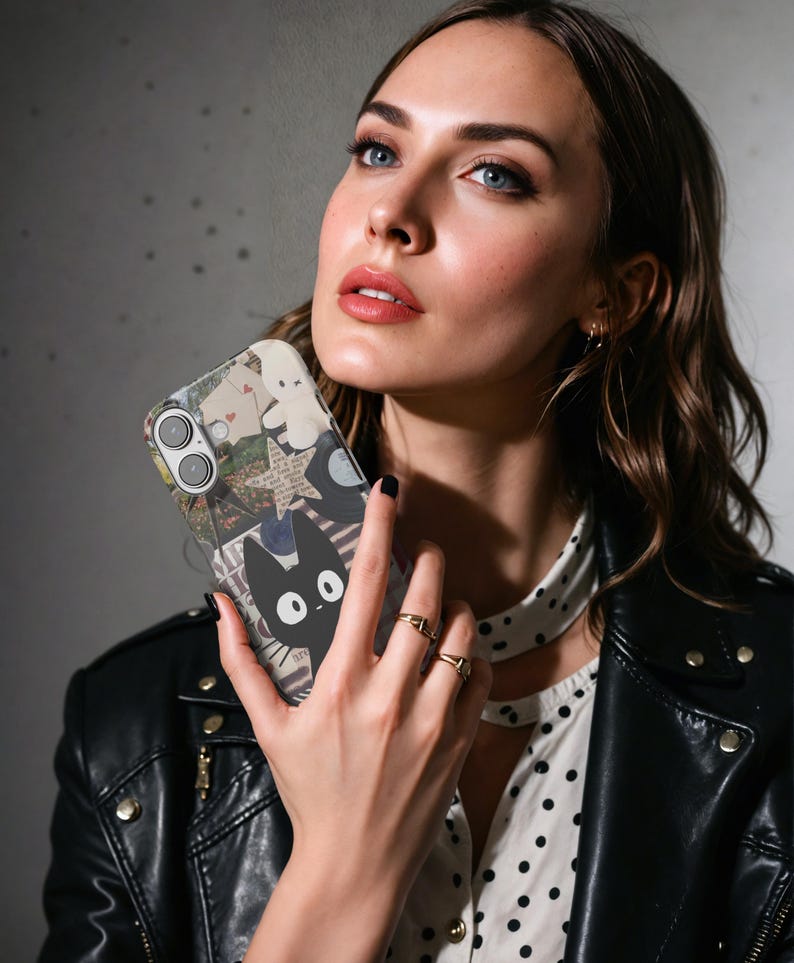 May include: A clear phone case featuring a collage design with a black cat illustration. The case has a dual-camera cutout and is held up by a person. The case has a black and white design.