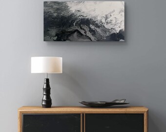Pode incluir: Uma pintura abstrata em preto e branco com padrões em espiral pendurada em uma parede cinza acima de um armário preto e de madeira com uma lâmpada no topo.