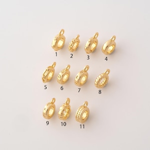 May include: Eleven gold-toned metal charms arranged in three rows, each featuring a central hole and a small loop at the top. The charms display various textures and patterns, including smooth, beaded, and star-like designs, labeled with numbers 1 through 11.