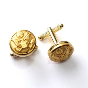 May include: A pair of gold cufflinks featuring the United States seal.