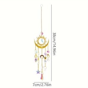 Op de afbeelding: Een goudkleurig hangend ornament van zon en maan met bungelende iriserende kristallen en sterren. Het ornament is 38 cm lang en 7 cm breed. Het zon- en maanontwerp heeft een hemels thema.
