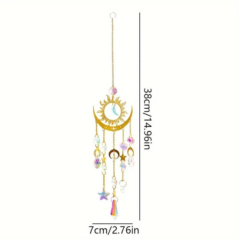 Op de afbeelding: Een goudkleurig hangend ornament van zon en maan met bungelende iriserende kristallen en sterren. Het ornament is 38 cm lang en 7 cm breed. Het zon- en maanontwerp heeft een hemels thema.