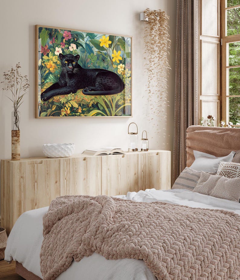 Op de afbeelding: Een ingelijste kunstdruk met een zwarte panter die rust te midden van weelderig groen en kleurrijke bloemen. Het kunstwerk, met zijn houten lijst, toont een gedetailleerde illustratie van de panter en zijn omgeving. De print is in vintage stijl.