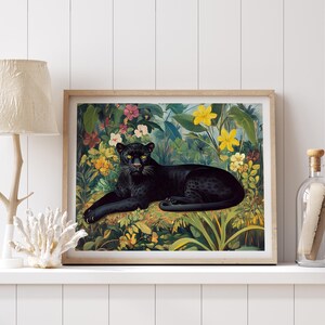 Op de afbeelding: Een ingelijste kunstdruk met een zwarte panter die rust in een weelderige, kleurrijke jungle-omgeving. Het kunstwerk toont levendige bloemen en bladeren, met de slanke vorm van de panter als middelpunt.