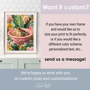 May include: Framed art print featuring a frog in a pink bowl surrounded by flowers. The artwork has a vintage aesthetic with a gold frame. The text "Want it custom?" and "send us a message!" are also visible.