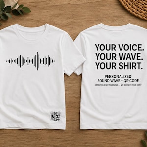 May include: A white t-shirt featuring a black sound wave graphic on the front with a small QR code near the bottom hem. The back of the shirt displays the text: YOUR VOICE. YOUR WAVE. YOUR SHIRT. PERSONALIZED SOUND WAVE + QR CODE. SEND YOUR RECORDING.