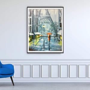 May include: An oil painting of a rainy street scene in Paris, featuring the Eiffel Tower. The artwork depicts a couple with an orange umbrella walking down a wet street. The painting is framed and hangs on a white wall.