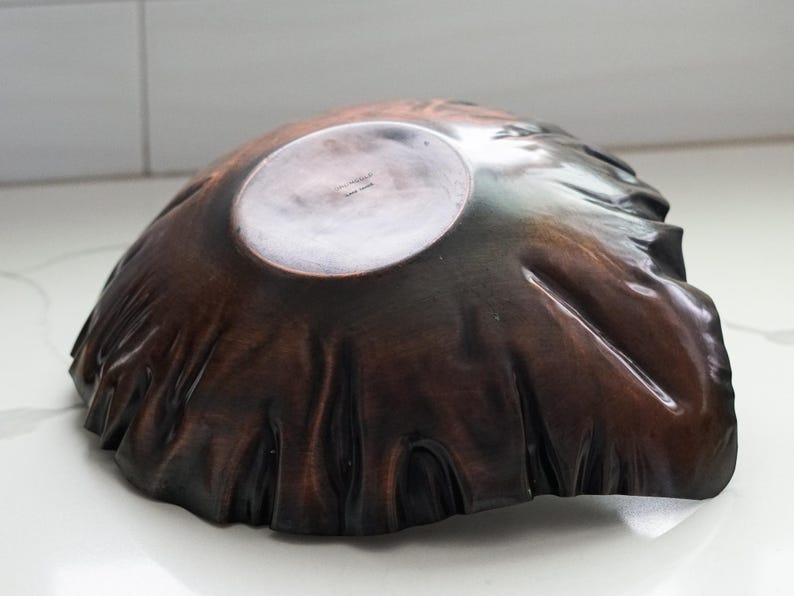 Puede incluir: Un cuenco de madera marr&oacute;n oscuro hecho a mano con una forma org&aacute;nica &uacute;nica. El cuenco tiene un interior liso y pulido y un exterior texturizado, que muestra la veta natural de la madera. El dise&ntilde;o del cuenco recuerda a una forma natural.