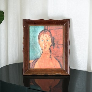 May include: A framed portrait of a woman with red hair and blue eyes. The painting has a warm color palette with a brown wooden frame. The background is a mix of teal and red.