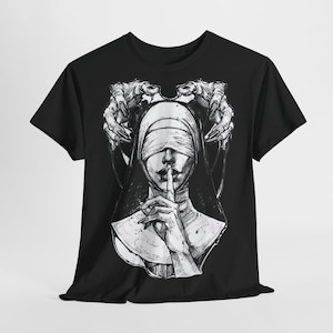Könnte beinhalten: Schwarzes T-Shirt mit einem grafischen Druck einer Nonne mit verbundenen Augen und dem Finger auf den Lippen. Die Nonne ist von einem Paar Händen umgeben, die sich ihr nähern.