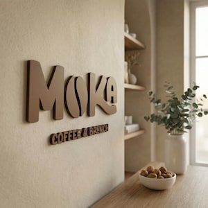 Può includere: Un'insegna da parete marrone con la scritta "Moka" e un design a chicco di caffè nella "O" e "Coffee & Brunch" sotto. L'insegna è montata su una parete beige. La scena comprende un tavolo in legno, mensole e un vaso con vegetazione.