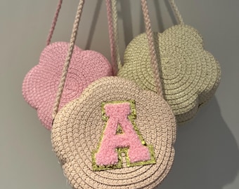 May include: Three pink and beige crocheted cloud-shaped purses with a pink fluffy letter 'A' on one of the purses.