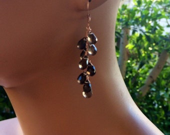 May include: Rose gold dangle earrings with a cascade of dark brown teardrop-shaped gemstones.