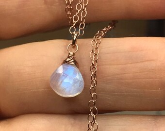 May include: A delicate rose gold chain necklace with a teardrop-shaped moonstone pendant.