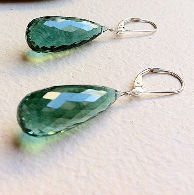 May include: A pair of silver earrings with teardrop-shaped green gemstone pendants.