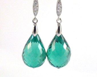 May include: A pair of silver dangle earrings with teardrop-shaped green gemstones.