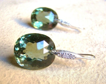 Peut inclure: Une paire de boucles d'oreilles pendantes en argent avec des pierres précieuses ovales vertes et de petites pierres claires sur le fil d'argent.