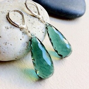 May include: A pair of silver dangle earrings with teardrop-shaped green gemstone pendants.