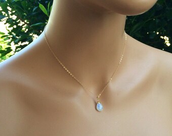 May include: A delicate gold chain necklace with a teardrop-shaped moonstone pendant.