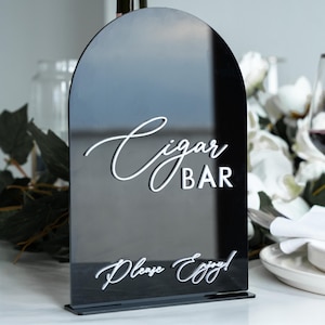 May include: Black acrylic arch sign with white text that reads "Cigar Bar" and "Please Enjoy!"