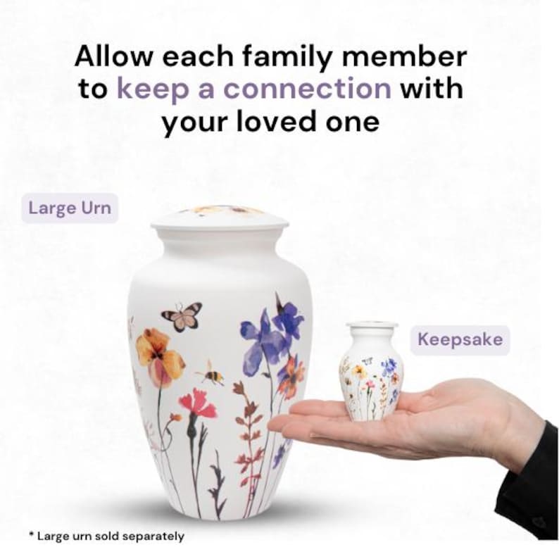May include: Two white ceramic urns with floral designs. The larger urn is labeled "Large Urn" and the smaller urn is labeled "Keepsake".