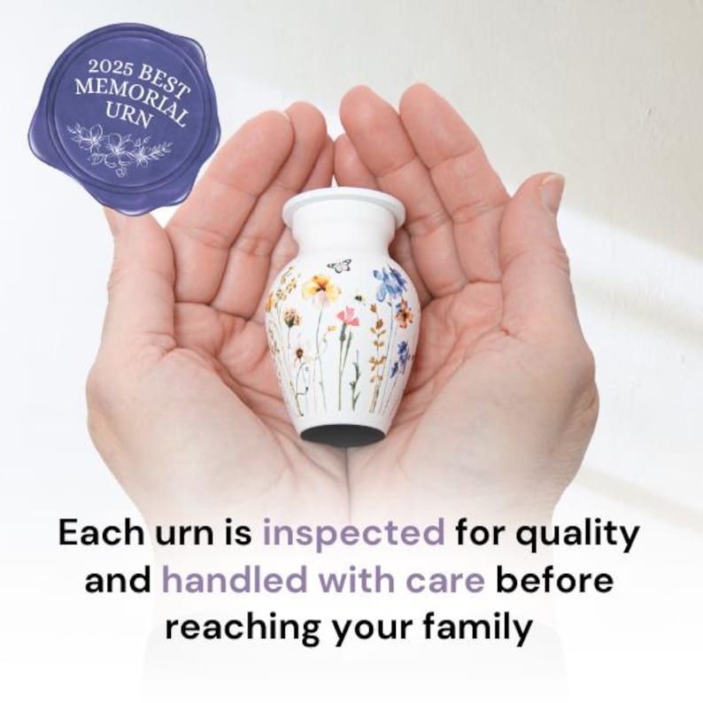 May include: White ceramic urn with a floral design. The urn is being held in two hands. The text "2025 Best Memorial Urn" is on a blue seal.