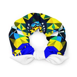 May include: A scrunchie with a vibrant geometric pattern in yellow, blue, green, and black, with a white bow. The design incorporates a crest with stars. This hair accessory is a stylish addition to any outfit.