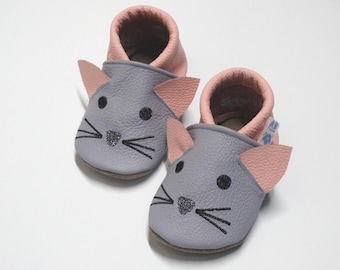 Könnte beinhalten: Ein Paar Babyschuhe im Maus-Design. Die Schuhe sind grau mit rosa Ohren und Innenfutter. Das Mausgesicht hat schwarze Augen, Schnurrhaare und eine glitzernde Nase. Die Sohlen sind hellbraun.