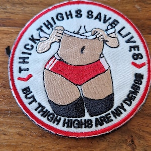 May include: Embroidered patch with a round design featuring a cartoon figure in red shorts and black stockings. The text "THICK THIGHS SAVE LIVES" and "BUT THIGH HIGHS ARE MY DEMISE" are in a circular pattern around the figure.
