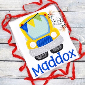 May include: A white t-shirt with a yellow school bus applique and the name Maddox in blue embroidery.
