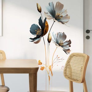 Könnte beinhalten: Ein Wandaufkleber mit einem floralen Design mit drei blauen und weißen Blumen mit goldenen Akzenten. Die Blumen befinden sich auf einem weißen Hintergrund.