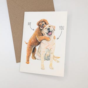 May include: Greeting card featuring a watercolor illustration of two dogs hugging, with the words "ME" and "YOU" pointing to each dog. A brown envelope is behind the card. The artist's name, "DEE-PHE", is in the bottom left corner.