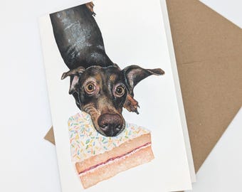 Könnte beinhalten: Ein brauner und schwarzer Dackel mit dem Kopf auf dem Kopf, der in die Kamera schaut. Der Hund hält ein Stück Kuchen mit weißem Frosting und bunten Streuseln.